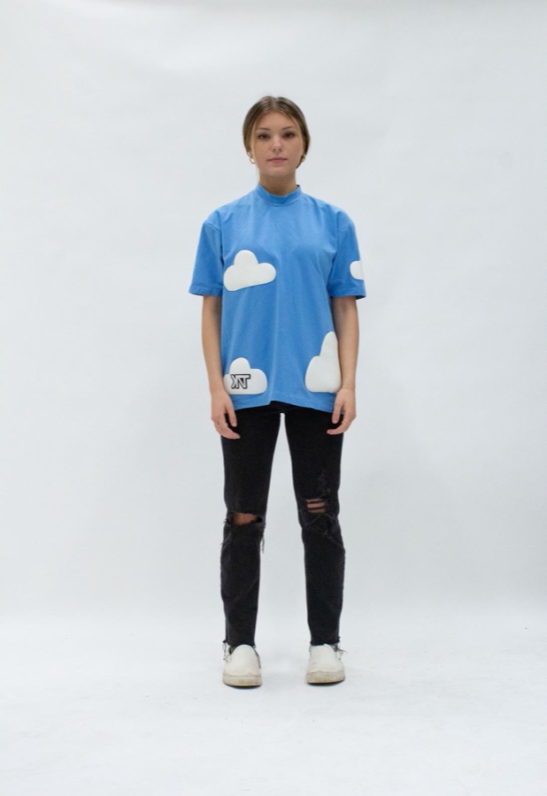 Cloud Tee — a sky blue tee with puffy white cloud appliqués and a small KNT tag stitched into one cloud